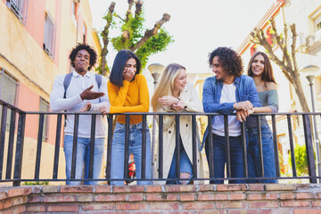Multiracial group of young people talking together in the street.