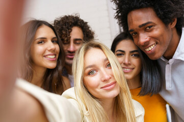 Fototapeta premium Multi-ethnic group of friends taking a selfie together while having fun outdoors.