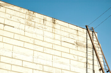 Modern warehouse building with an iron staircase casting shadow on te wahite wall