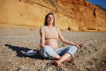 Fototapeta na wymiar pregnant woman sitting on yellow rock and meditating