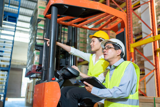 workers team meeting and training working at warehouse.Manager asian man in safety with white hardhat standing with check order with tablet.Female asia worker at large Warehouse in forklift loader
