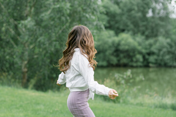 Obraz premium Happy girl with long wavy hair blowing in the wind in nature