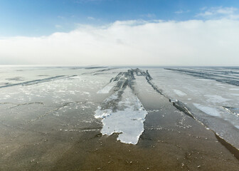 winter landscape by the sea, snowy, interesting ice shapes on the sea shore, dunes covered with a white layer of shining snow