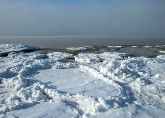 winter landscape by the sea, snowy pieces of ice by the sea, dunes covered with a white layer of shining snow
