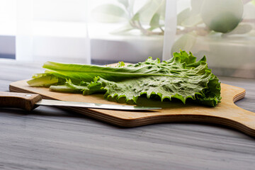 lettuce leaves on a cutting board next to a knife on the table