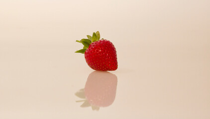 Single strawberry reflected in neutral background with space for copy