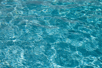 Blue pool water background. Blurred transparent clear calm water surface texture. Water waves in sunlight with copy space.