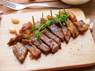 Beef steak sliced with fresh rosemary herb on top.