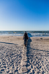 woman walking on the breakwater on the beach in Leba.