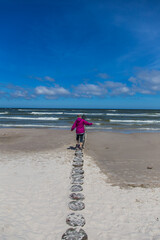woman walking on the breakwater on the beach in Leba.