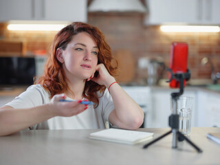 Technology and blogging concept. Redhair woman recording video concent for her blog at home