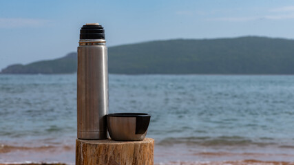 Touristic thermos with tea by the sea 