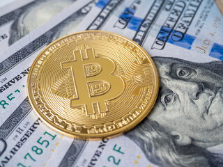 yellow bitcoin lies on hundred-dollar bills. The concept of cryptocurrency, investment, income