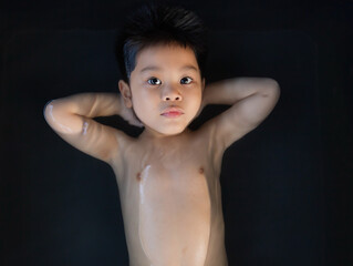 Cute boy soaking in a black bath tub