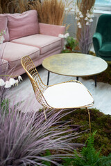 A golden chair with a mesh back stands on the moss. Eco design.Stylish interior with cereals and dried flowers.