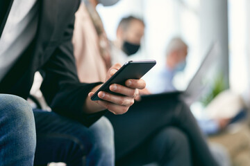 Close-up of male candidate using mobile phone while waiting for job interview.