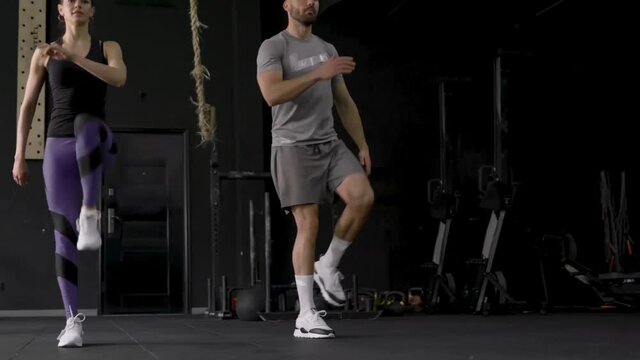Fitness couple in sportswear doing flexion lunges exercises at gym slow motion.