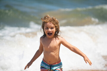 Excited little kid boy playing at the sea beach.