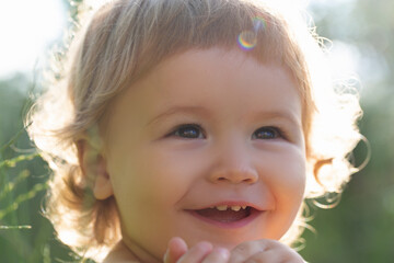 Kids portrait, close up head of cute child. Baby smiling, cute smile on sunny day. Cropped face outdoor.