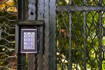 Secure password on keyboard for opening door. Metal code lock. Background of trees in the park.