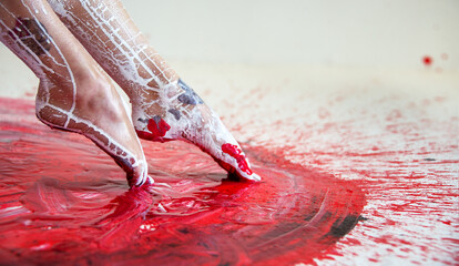 Young artistic abstract painted woman ballerina with black and white color, her feet in red color,...