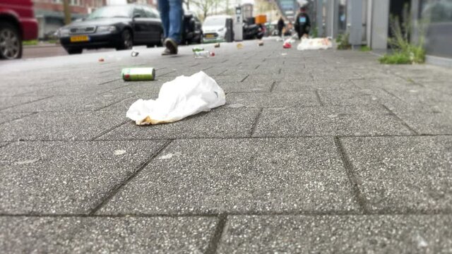 Selective focus. Garbage on the city sidewalk near metal trash bin. Environmental protections 1