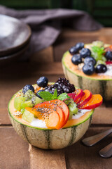 Fruit salad with yogurt in carved melon cantaloupe bowl