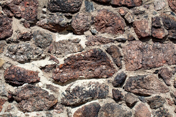 Fragment of the wall of the old house, stone masonry made of natural granite.