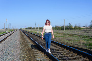 Teenage girl walks on the railroad tracks