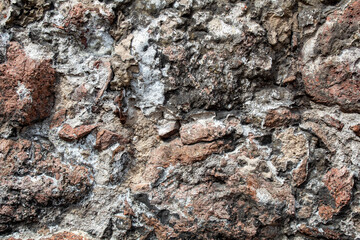 Fragment of the wall of the old house, stone masonry made of natural granite.