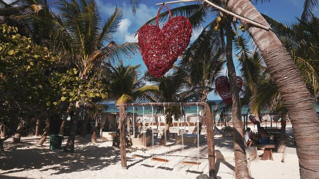 Beautiful beach paradise concept. Floating herts hanging form the palm, bath on the beach, copal smoke and beautiful resort. Palms trees in the background.
