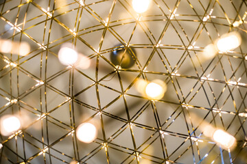 Detail of a modern LED light chandelier on a white background and gold colored metal