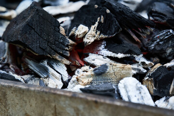 Glowing charcoals in a rusty barbecue grill. View diagonally from the front. Pattern.