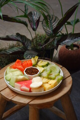 a plate of salad fruits served with sweet and spicy sauce named rujak buah in bahasa