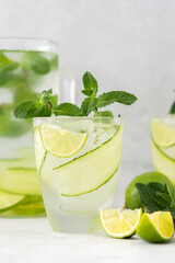 Cold refreshing drinks with lime and cucumber, summer iced beverage and fresh green mint, glass with lemon water close up
