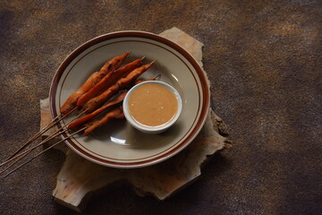 a plate of chicken satay served with peanut sauce 