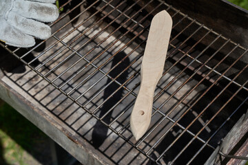 Wire brush and protective hand glove on dirty grill rust. Tool casts dark shadow. Oblique from...