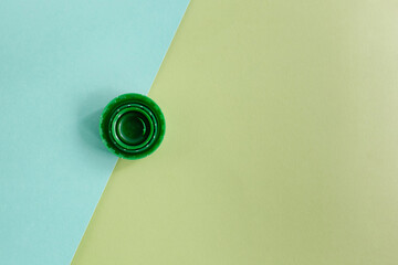 Top view of few green plastic bottle cups folded one into the other on bright green and turquoise background.
