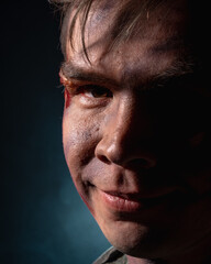 Portrait of a close-up of a soldier in scars and battle coloring on a black background with blue smoke