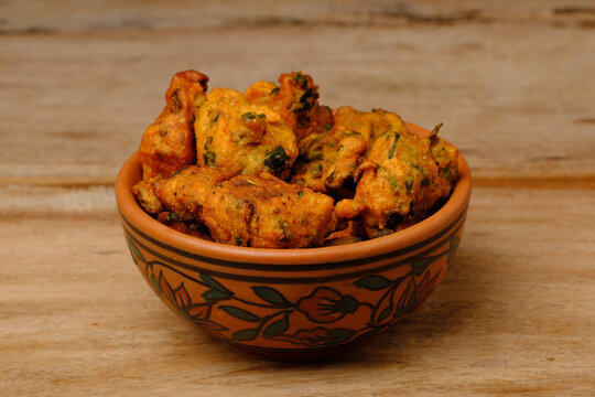 Indian snack pakora in a bowl on wooden background