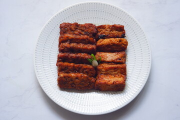 a plate of tempeh and tofu cooked in sweet soy sauce 