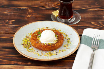 Turkish dessert kunefe with ice cream ball on wooden background