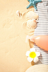 Summer beach, travel, holiday, vacation concept. Tube of sunscreen, starfish, plumeria frangipani and seashells on the sand. Top view. Copy space.