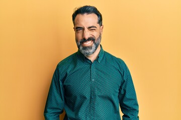 Fototapeta premium Middle age man with beard and grey hair wearing business clothes winking looking at the camera with sexy expression, cheerful and happy face.