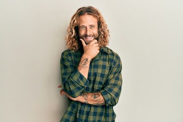 Handsome man with beard and long hair wearing casual clothes looking confident at the camera smiling with crossed arms and hand raised on chin. thinking positive.