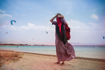 bedouin wife in a flying dress on the beach of the blue lagoon sells jewelry - obrazy, fototapety, plakaty