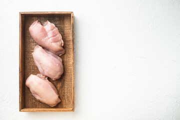 Chicken breast fillets, in wooden box, on white stone  background, top view flat lay, with copy space for text