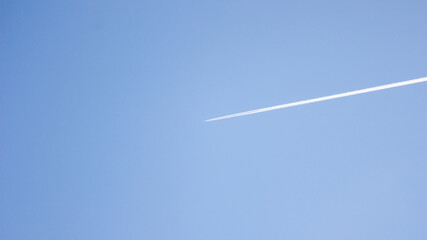 The white stripe is the trail of a plane flying high in the sky against a blue sky background.
