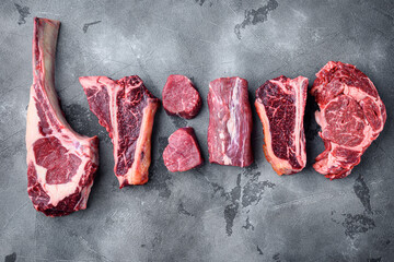 Various cuts of marbled beef meat and dry aged steaks, tomahawk, t bone, club steak, rib eye and tenderloin cuts, on gray stone background, top view flat lay, with copy space for text - Powered by Adobe