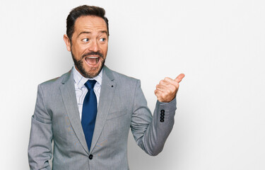 Middle age man wearing business clothes smiling with happy face looking and pointing to the side with thumb up.